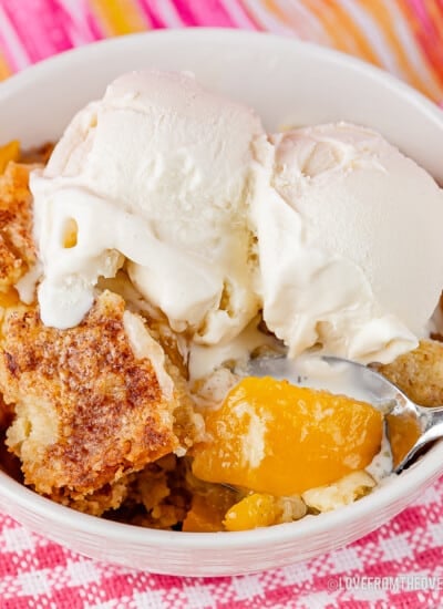 Bowl of peach dump cake topped with vanilla ice cream