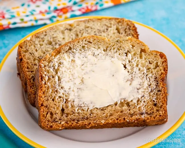 Two slices of banana bread, one with butter spread on it