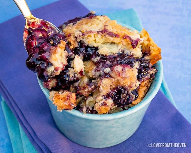 Bowl of blueberry dump cake with a blue background
