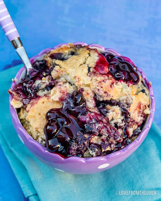 Bowl of Blueberry Dump Cake on a blue background