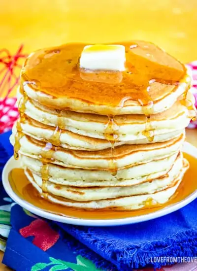 A stack of buttermilk pancakes topped with syrup and butter