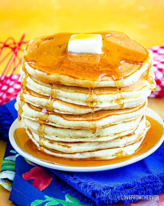 A stack of buttermilk pancakes topped with syrup and butter