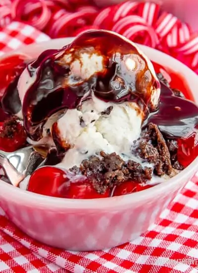 A bowl with chocolate cake, ice cream and cherries