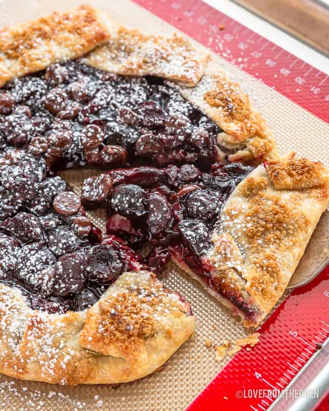 Cherry galette on a baking sheet having a piece taken out