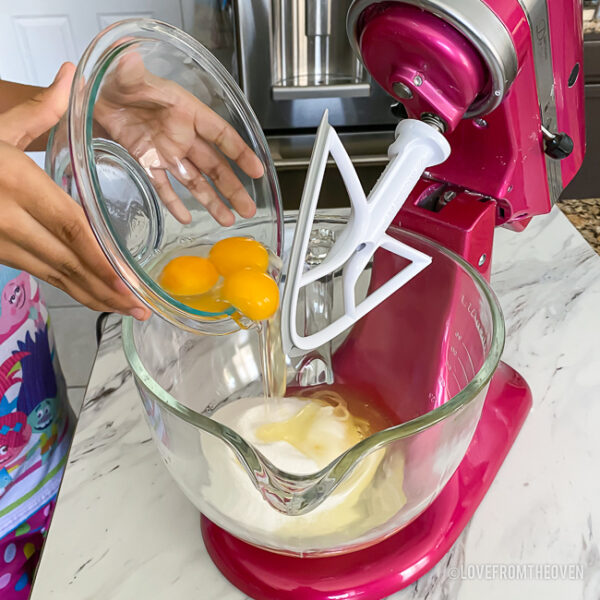 eggs being poured into a stand mixer
