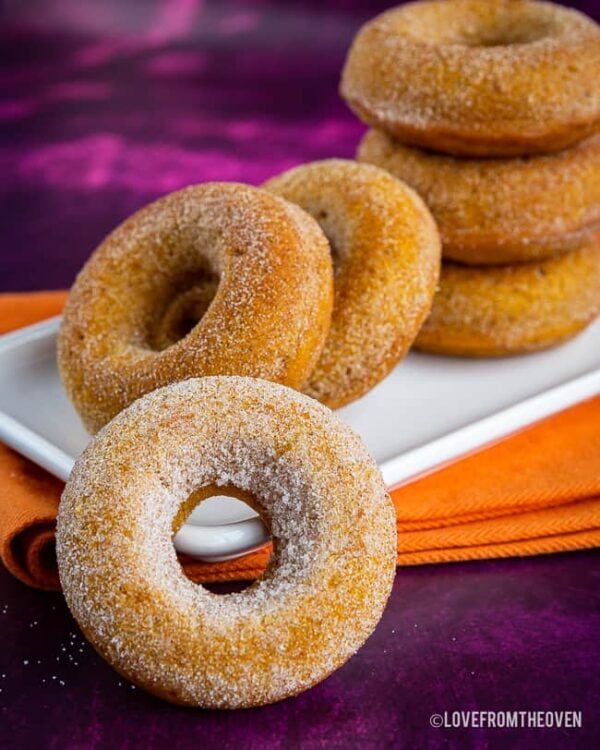 Six pumpkin donuts on a purple background