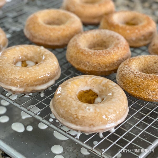 Pumpkin donuts with glaze sitting on a wire rack