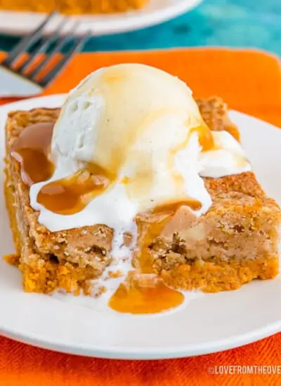 Pumpkin dump cake topped with ice cream on a white plate