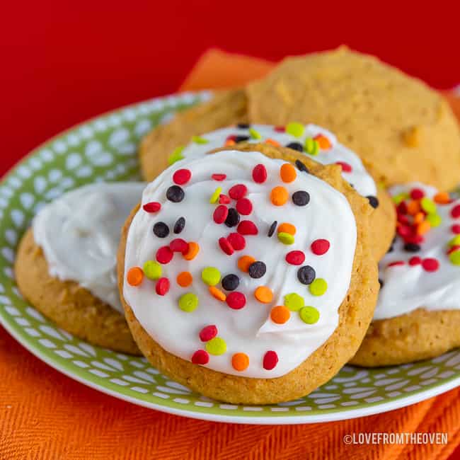 A plate of pumpkin cookies, some with frosting and sprinkles