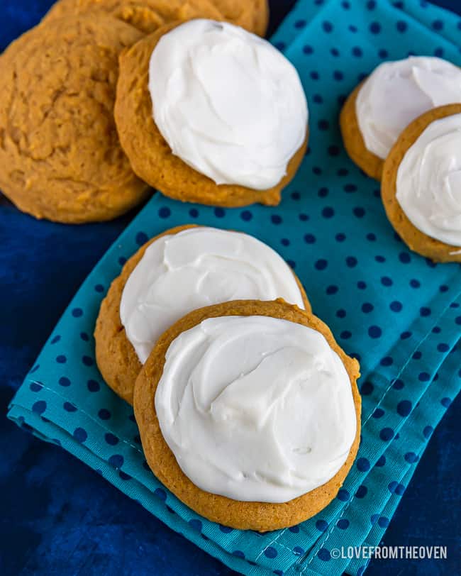 Plain and iced pumpkin cookies on a blue napkin