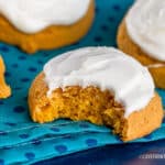 Pumpkin cookies with icing with one that has a bite taken out of it