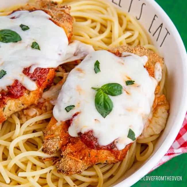 Chicken parmesan in a bowl over spaghetti noodles