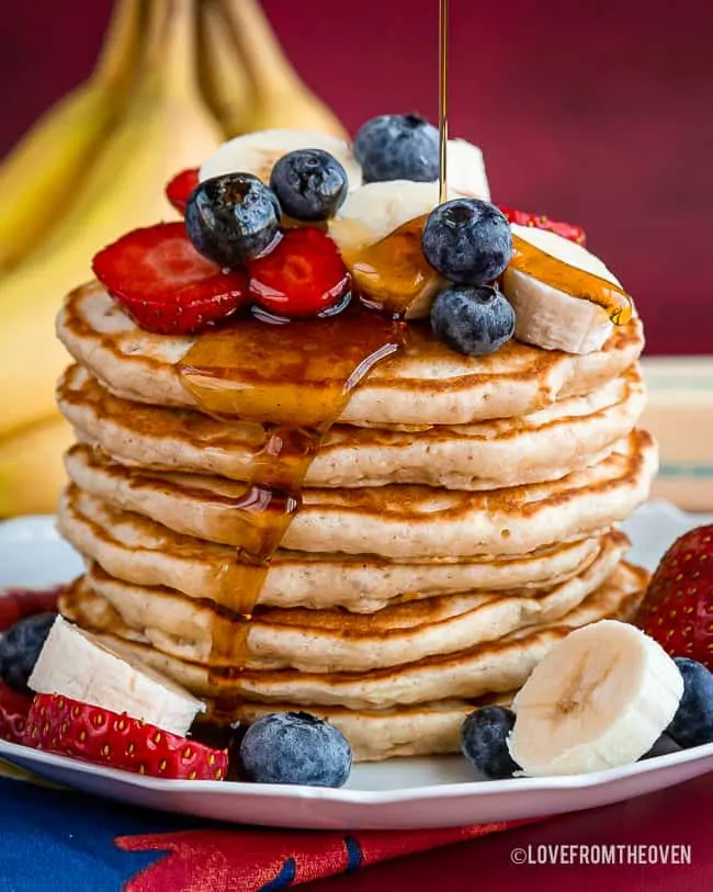 Stack of banana pancakes with berries and bananas on top