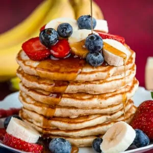 plate of pancakes topped with fruit and syrup