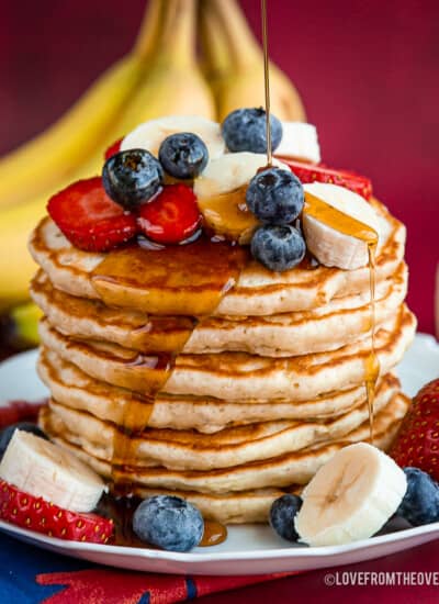 plate of pancakes topped with fruit and syrup