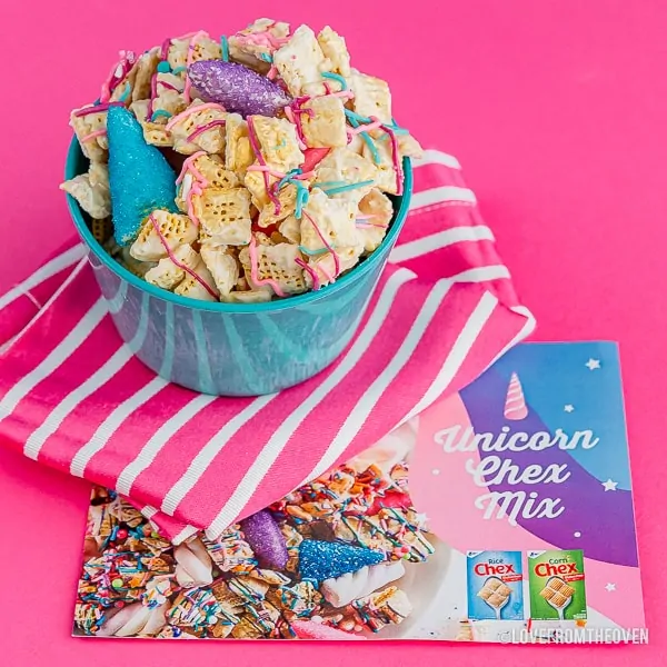Chex mix in a blue bowl on a a pink backround with recipe instructions