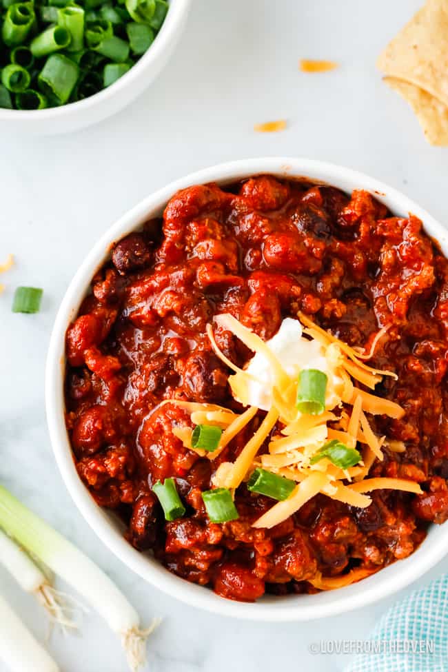 bowl of crockpot beef chili topped with sour cream and cheese