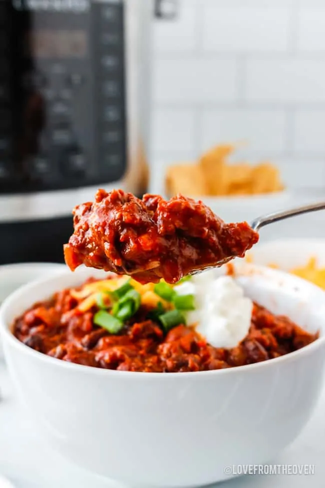 spoonful of beef chili in front of a bowl of chili