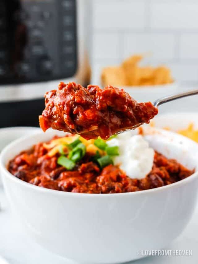 spoonful of beef chili in front of a bowl of chili