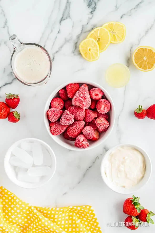 Ingredients to make a frozen fruit smoothie on a marble background