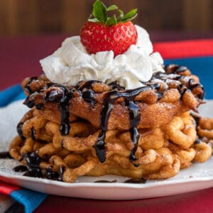 a stack of funnel cakes topped with whipped cream