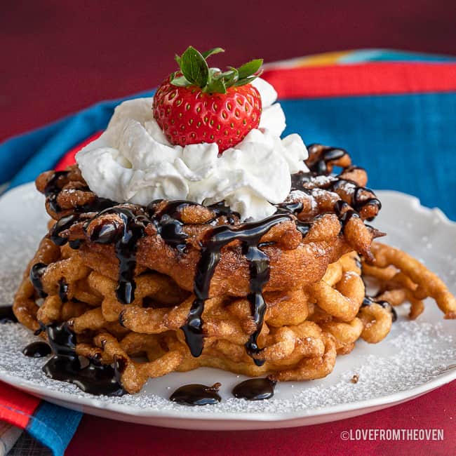 Funnel cake topped with chocolate sauce, powdered sugar and whipped cream