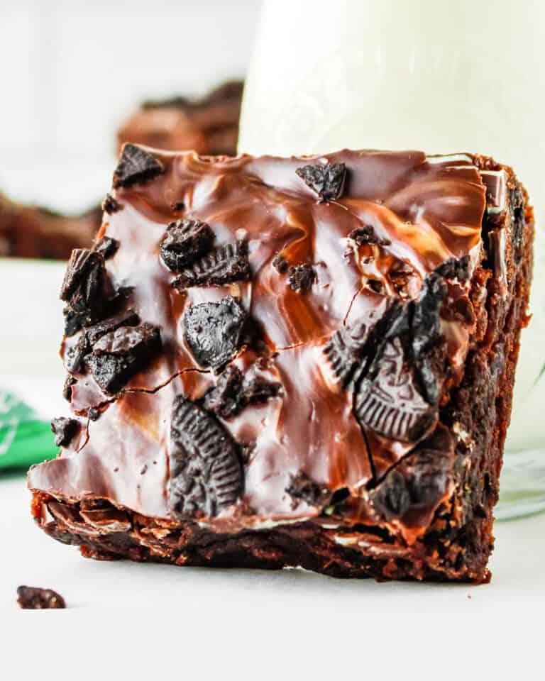 A mint oreo brownie sitting against a glass of milk