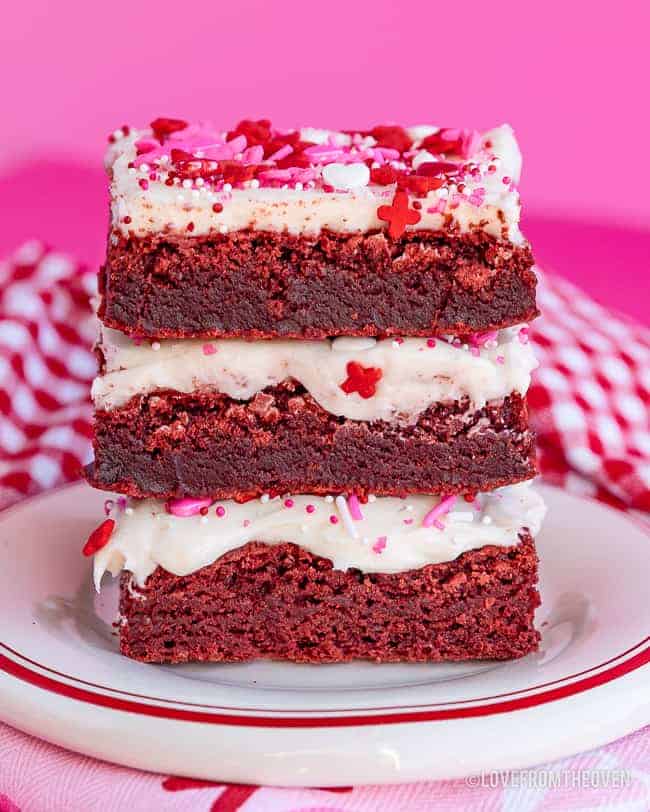 stack of red velvet brownies with frosting and pink and red sprinkles