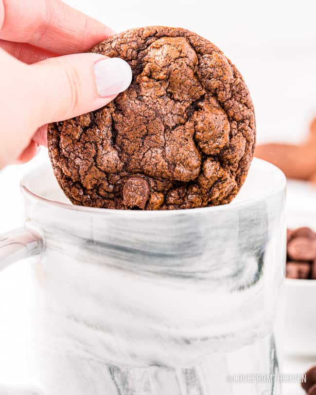 A brownie cookie being dunked into milk