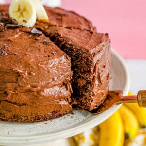 A slice of cake being taken from a chocolate banana cake