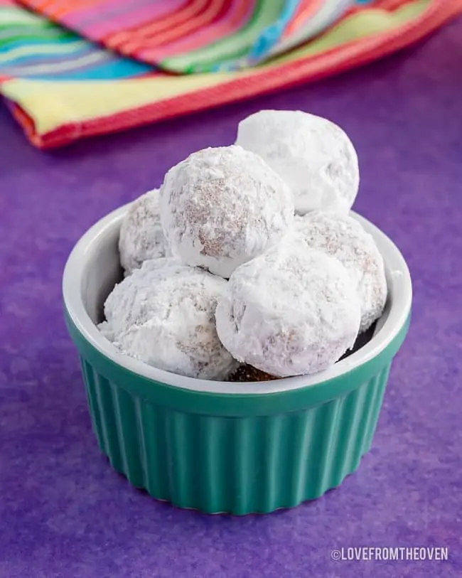 a bowl of pancake mix donut holes covered in powdered sugar