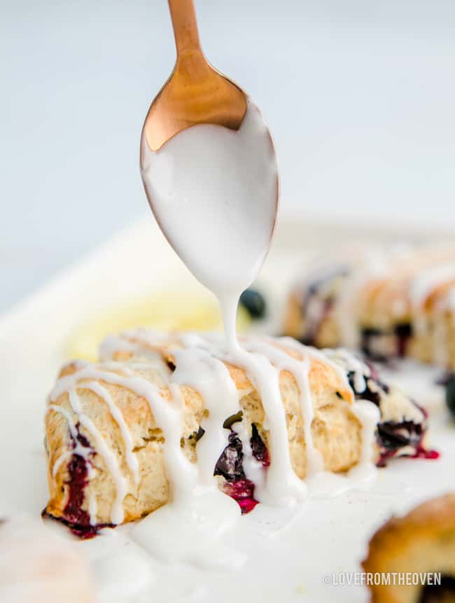 a spoon putting lemon glaze on blueberry scones