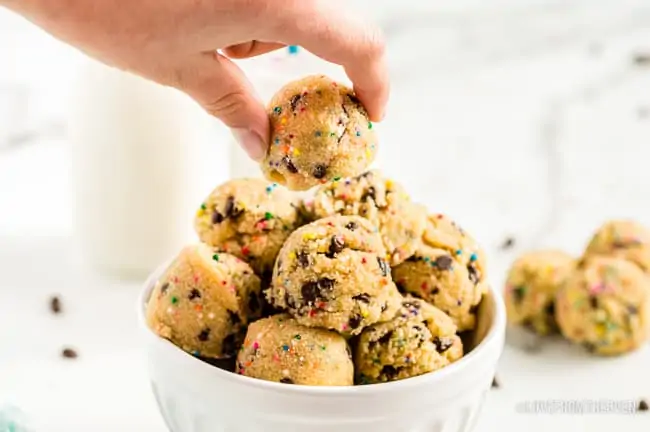 someone taking a cookie dough bite from a white bowl
