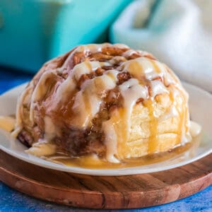 a cinnamon roll on a white plate with a blue background