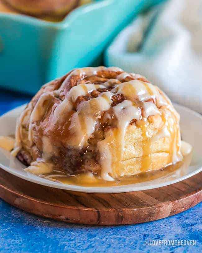 a cinnamon roll on a white plate with a blue background