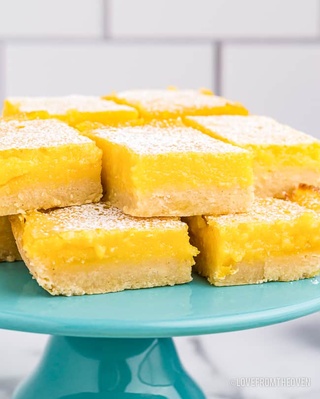 a stack of lemon bars on a blue cake stand