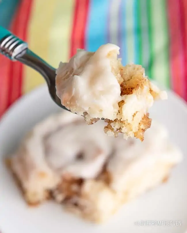 A close up of a bite of cinnamon roll on a fork