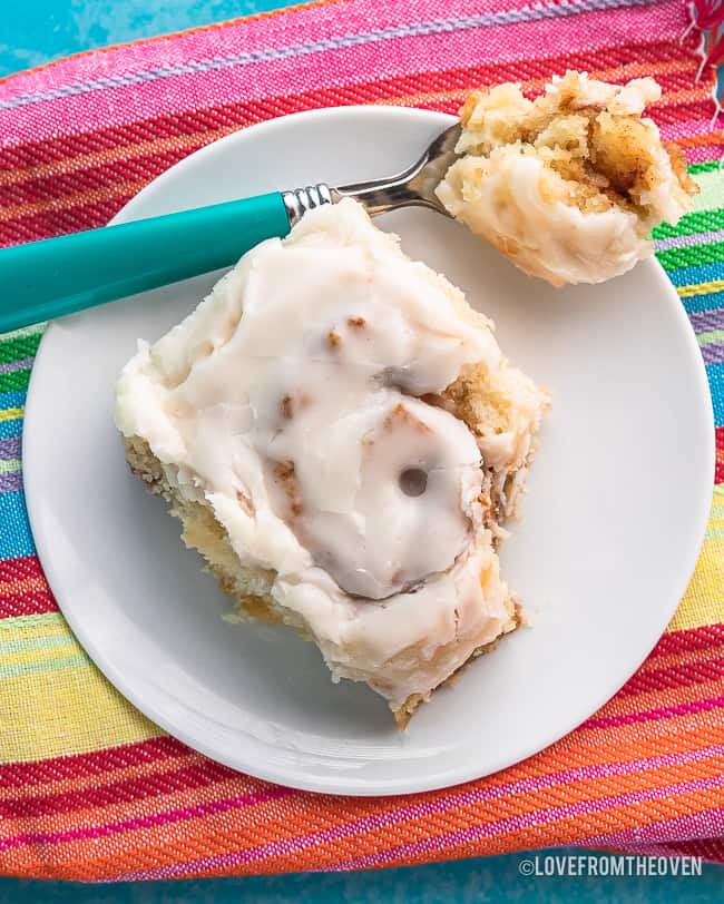 An overhead photo of a cinnamon roll on a striped towel