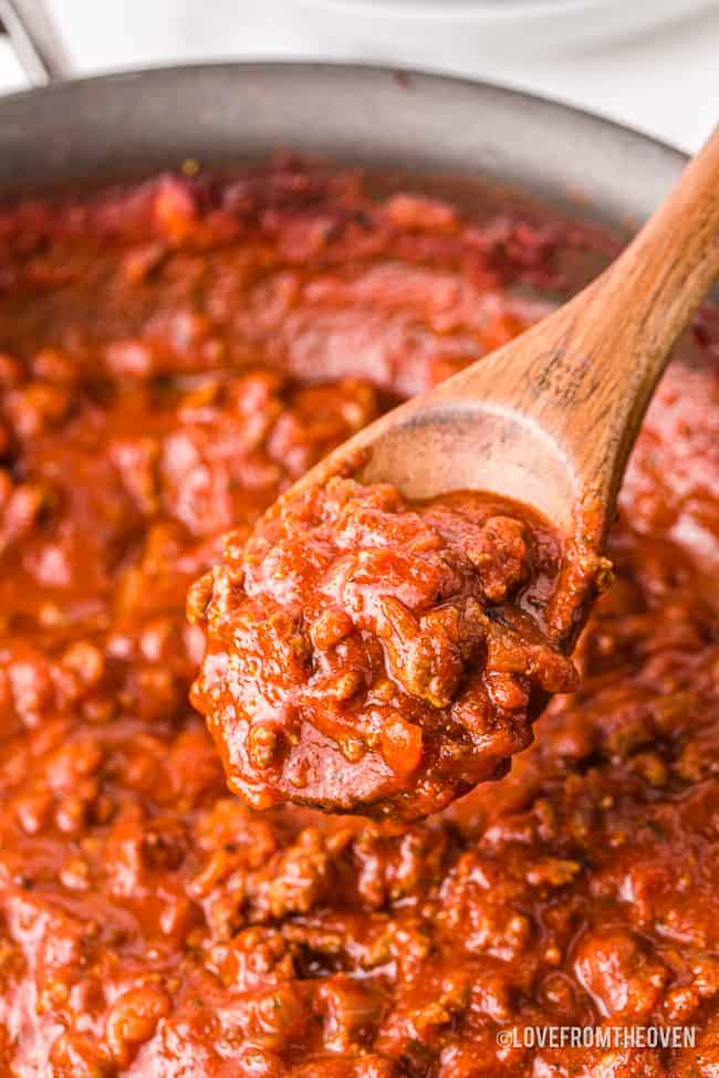 A pan of homemade spaghetti sauce with a spoon stirring