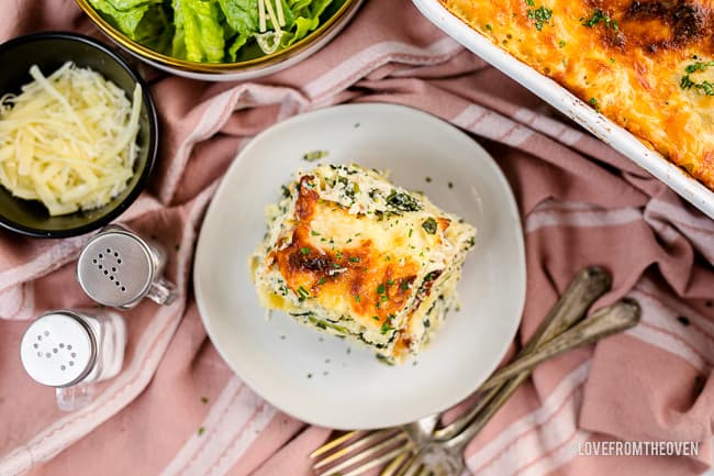 An overhead photos of chicken alfredo lasagna on a table with a pink tablecloth