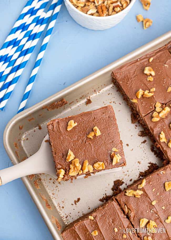 Overhead photo of a slice of chocolate sheet cake being taken from a pan