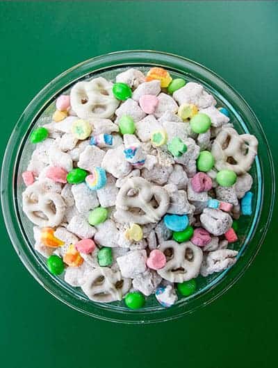 A bowl of muddy buddies on a green background