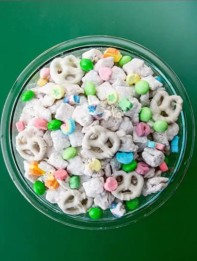 A bowl of muddy buddies on a green background