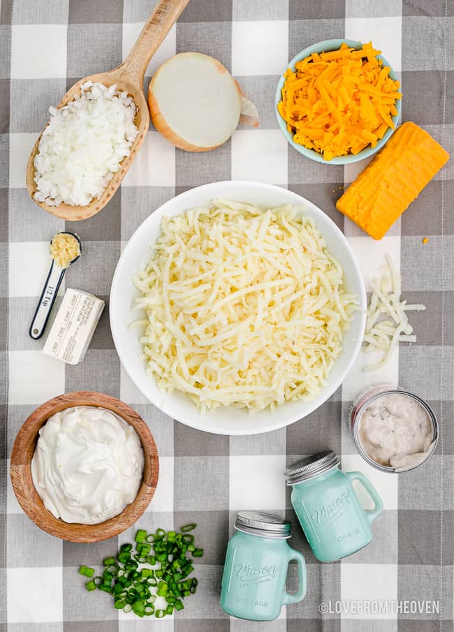 ingredients to make cheesy hashbrown casserole on a gingham background