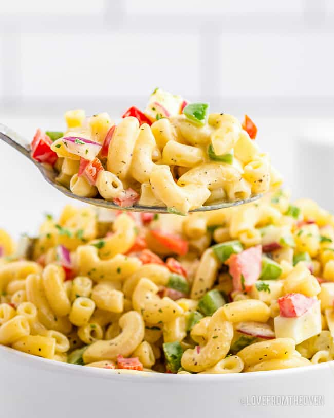 A spoon taking a serving of macaroni salad