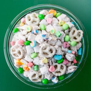 a bowl of muddy buddies on a green background