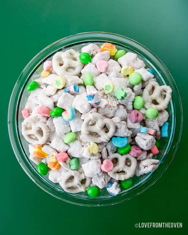 a bowl of muddy buddies on a green background