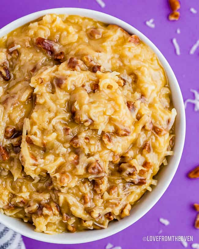 a bowl of coconut pecan frosting on a purple background