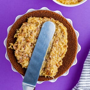 spreading german chocolate cake frosting onto a cake