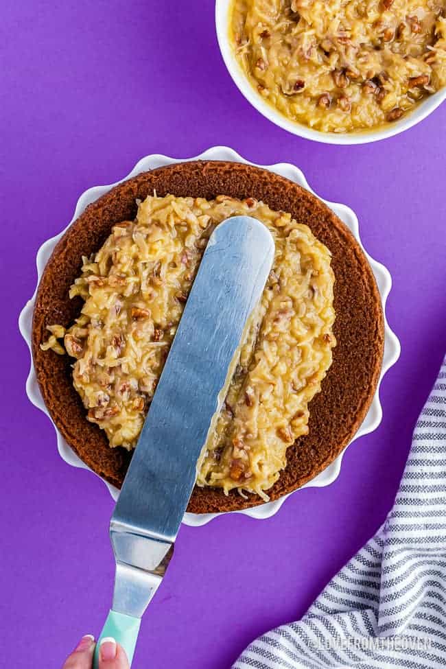 spreading german chocolate cake frosting onto a cake